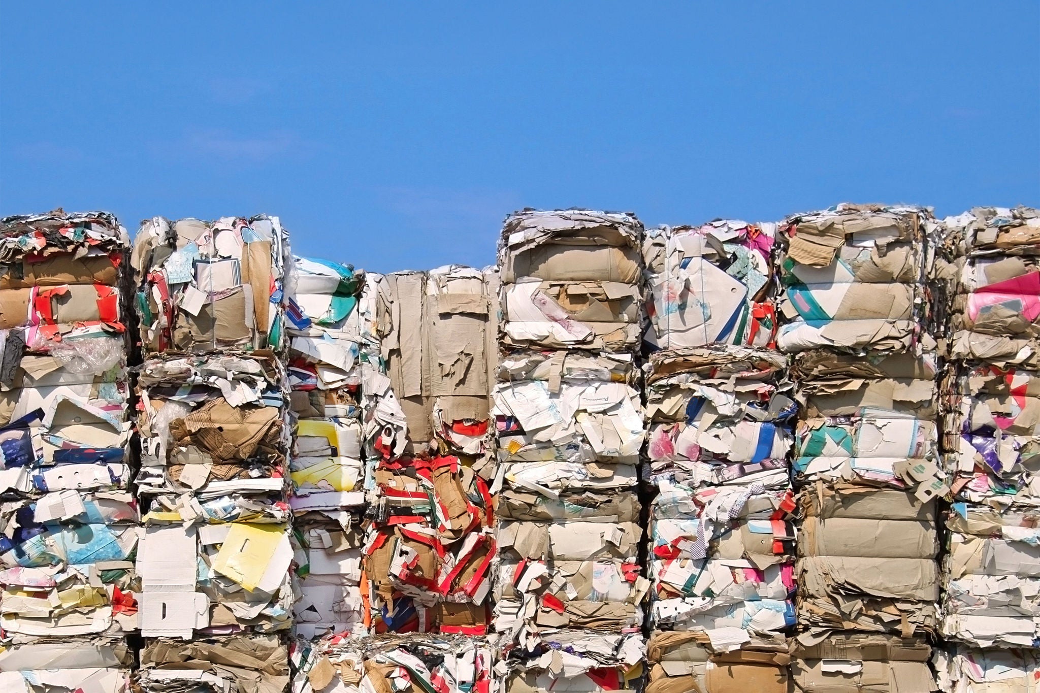 Gestapeltes recyceltes Papier vor blauem Himmel