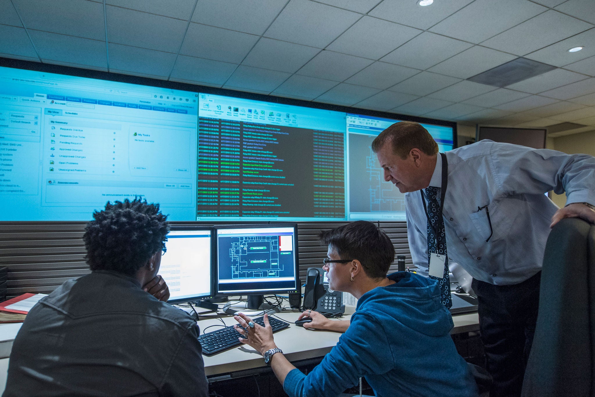 IT professionals monitor dashboards and code in a control room for system operations and security