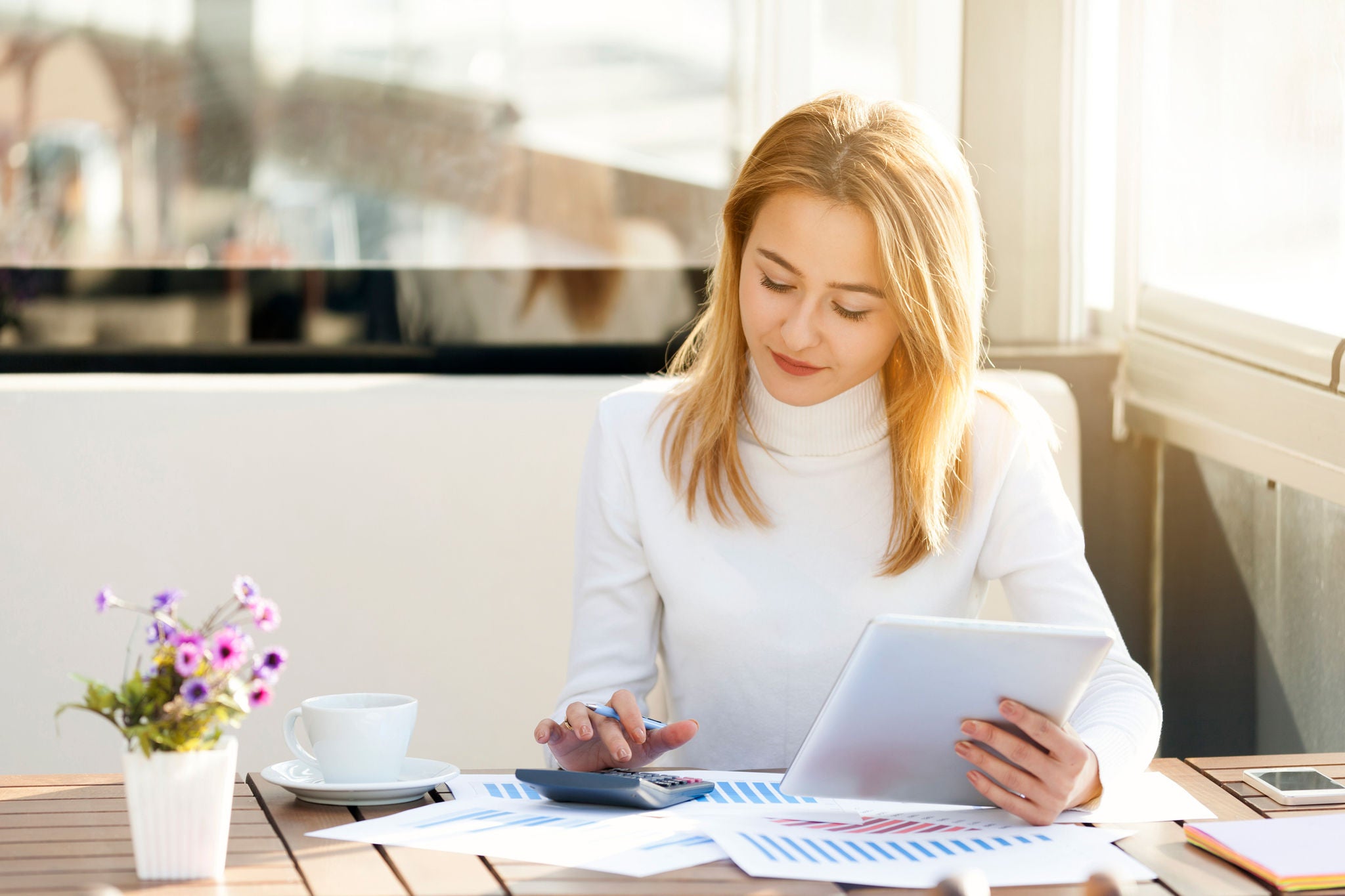 Woman reviews charts on paper while using a tablet