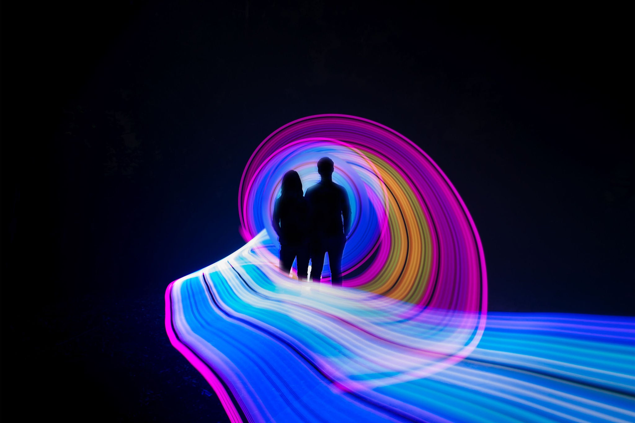Two people standing in the center of a light painting.