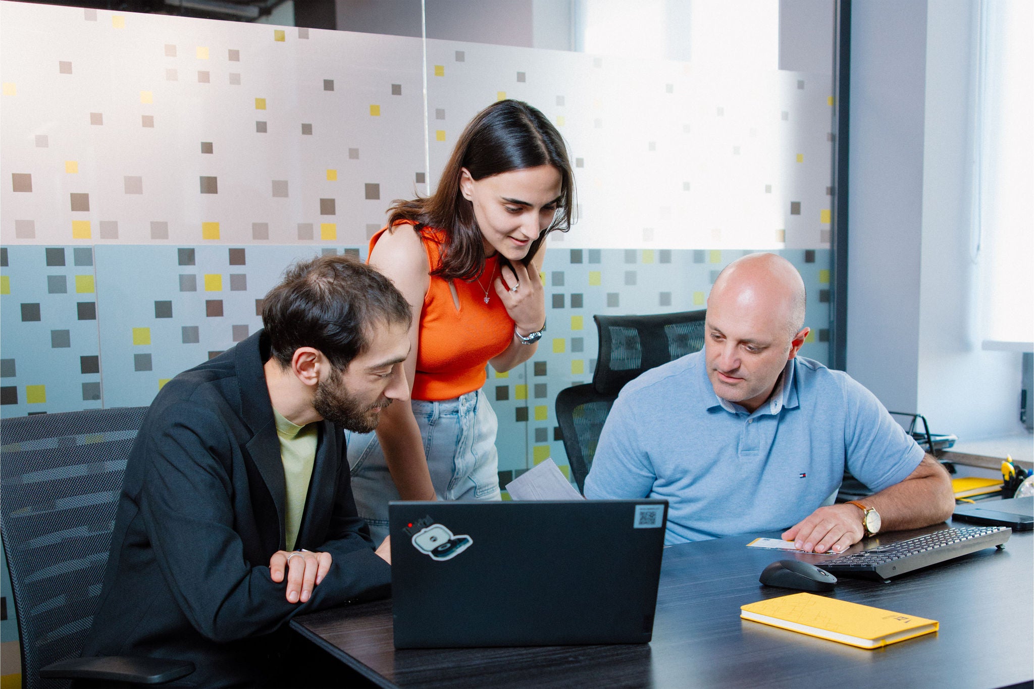 Business professionals collaborating around a laptop in an office.