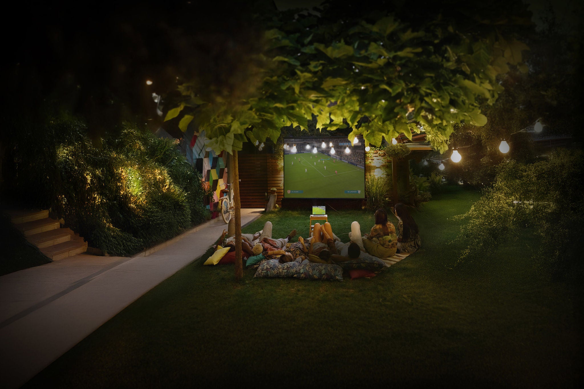 Carefree friends watching football on an outdoor screen at night