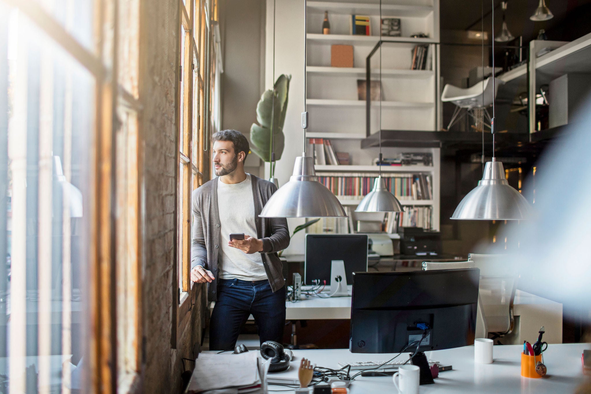 Young entrepreneur looking through the window in the office