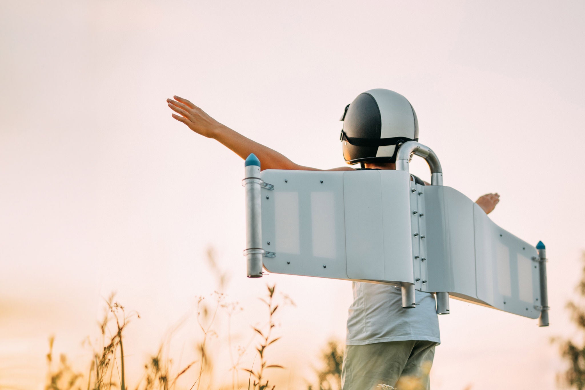 Kind mit Jetpack-Flügeln und rennt auf Feldern