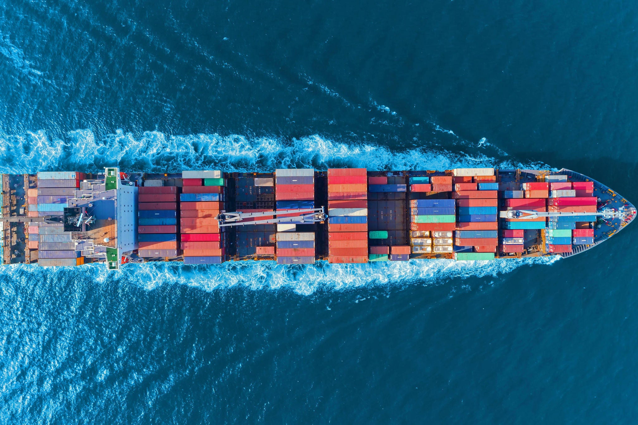 Aerial top view full speed container ship in the sea for logistics import export, shipping or transportation concept.