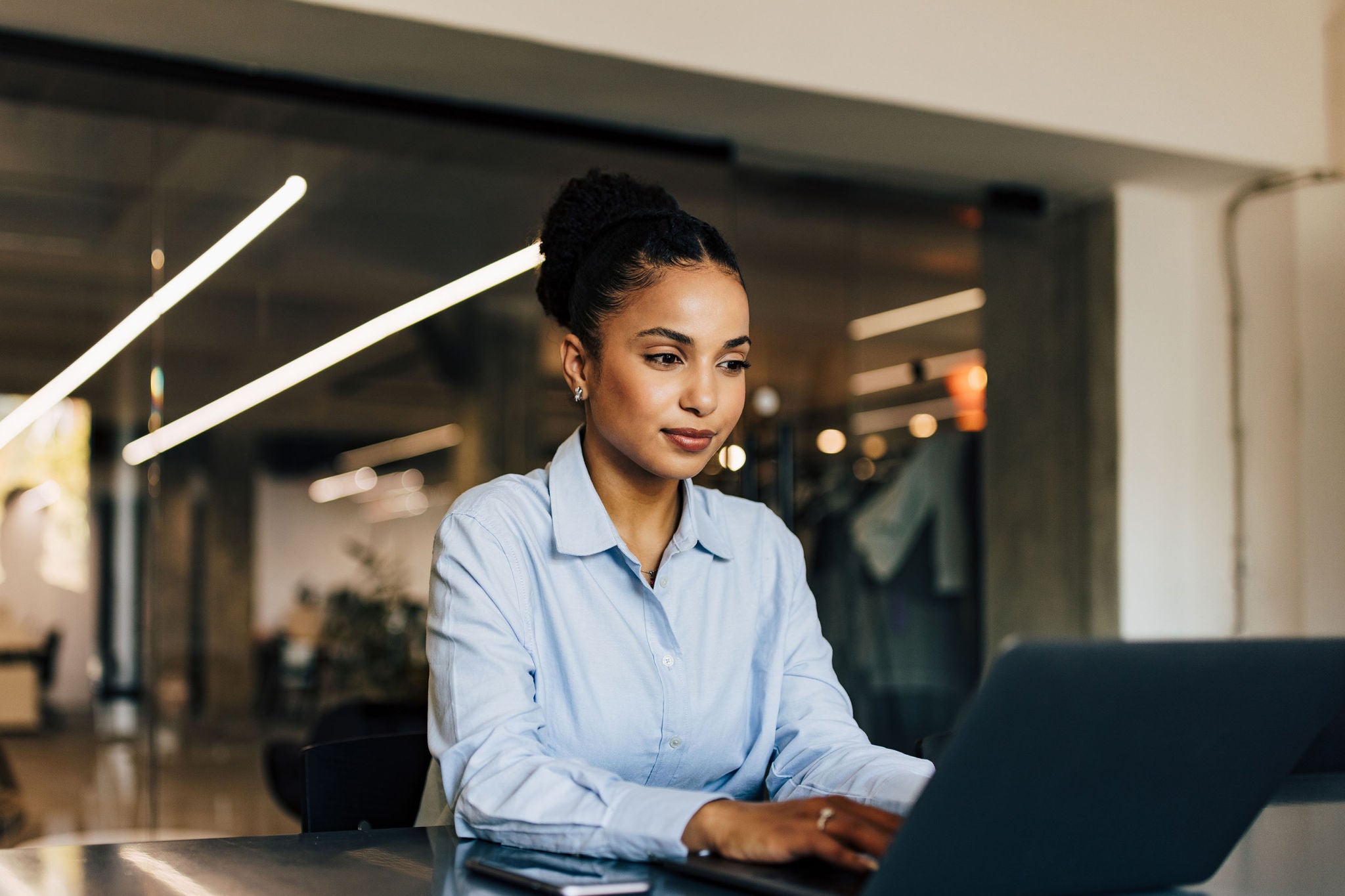Woman sitting at the office and typing something on the laptop.
