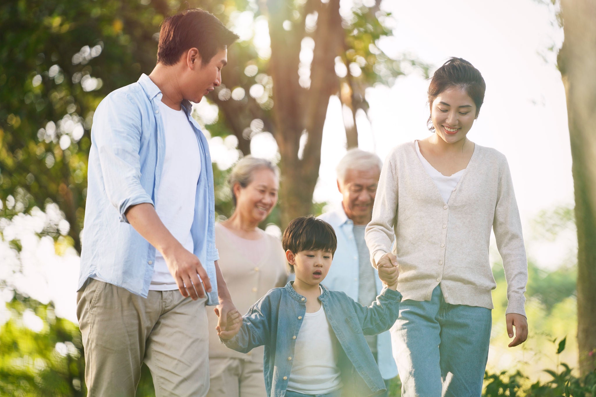 three generation happy asian family walking outdoors in park