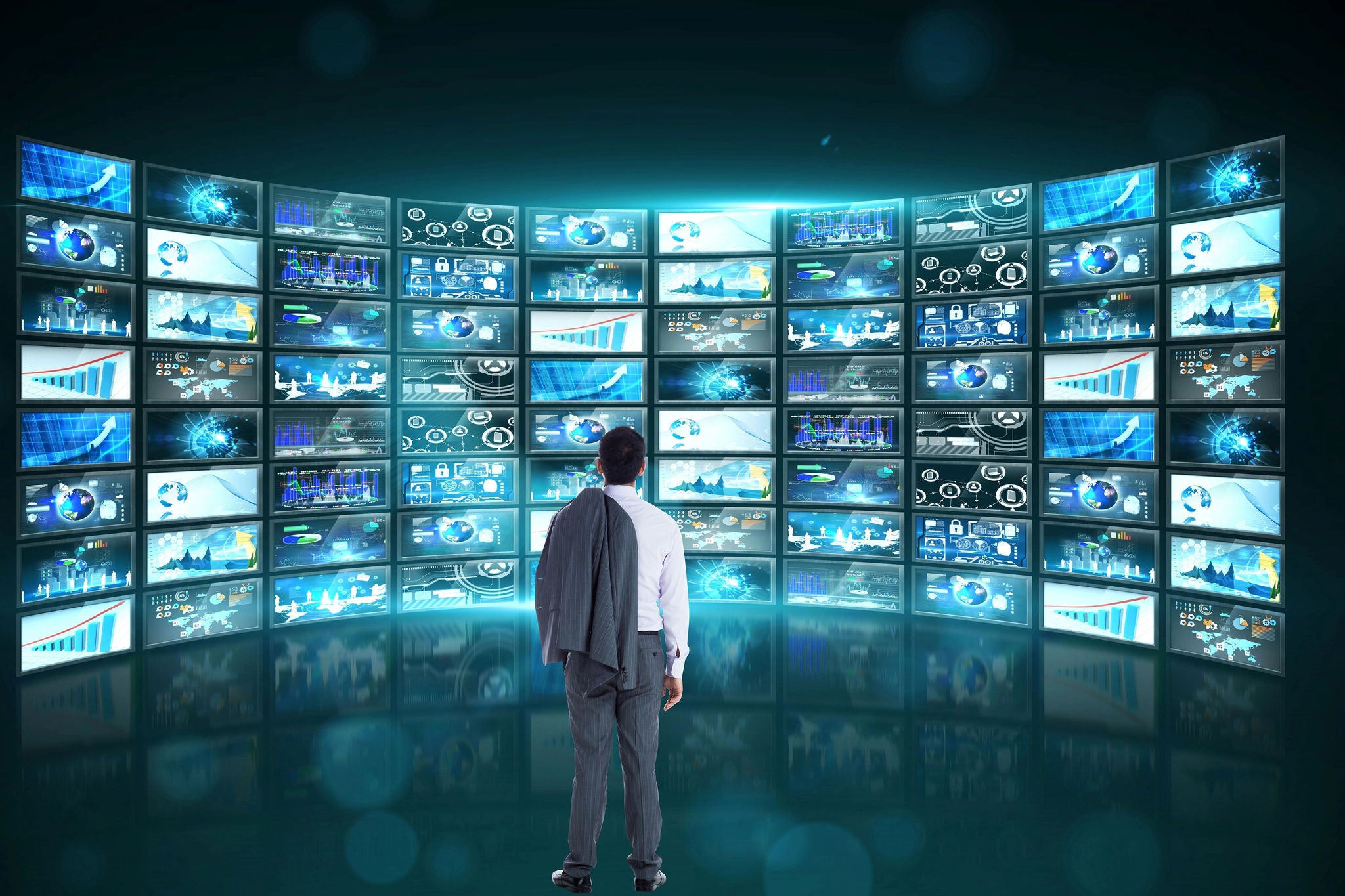 Person vor einer digitalen Videowand mit Datenvisualisierungen, Diagrammen und vernetzten Informationen.