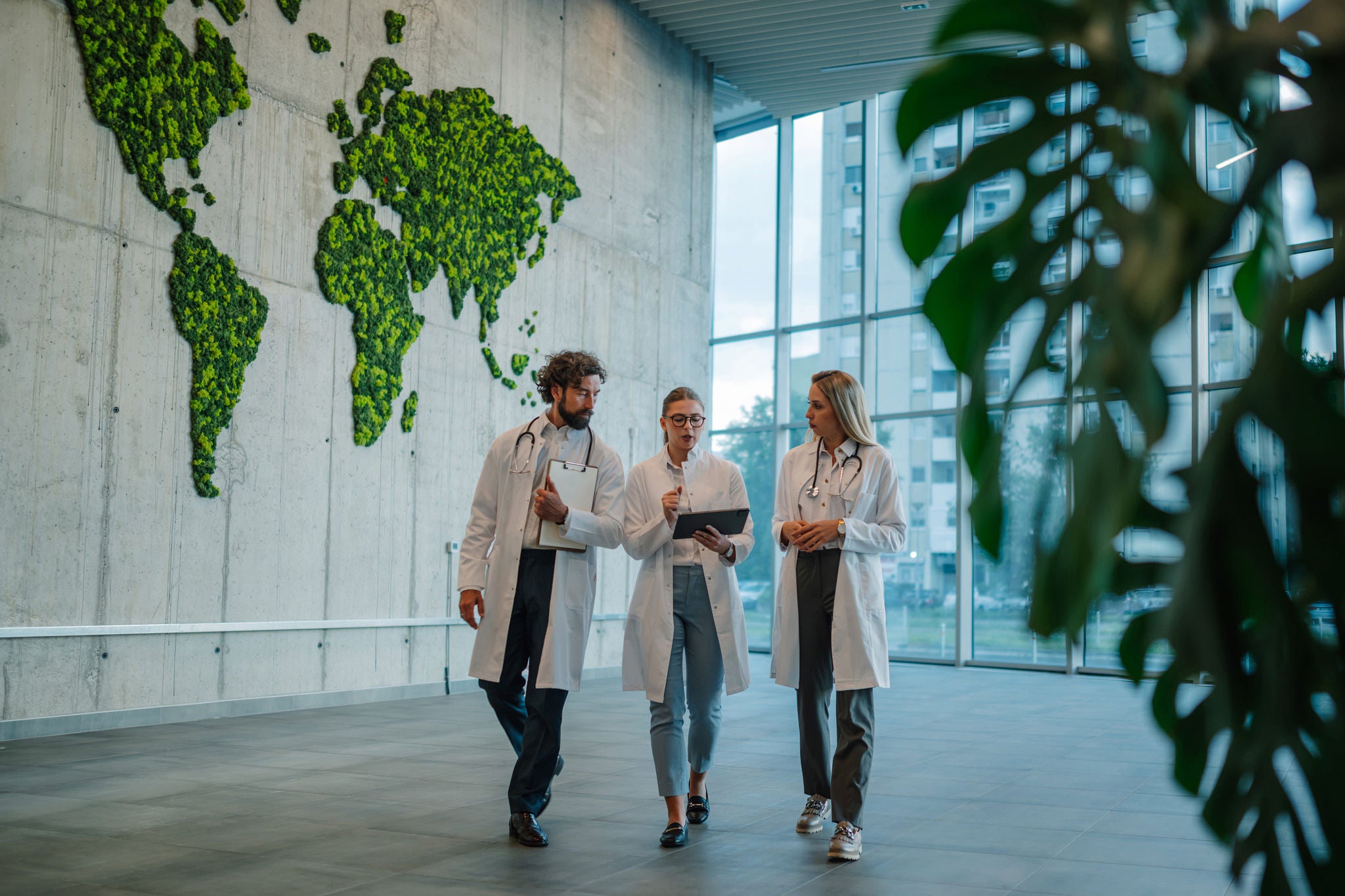 Three doctors discussing a diagnosis in a modern hospital lobby