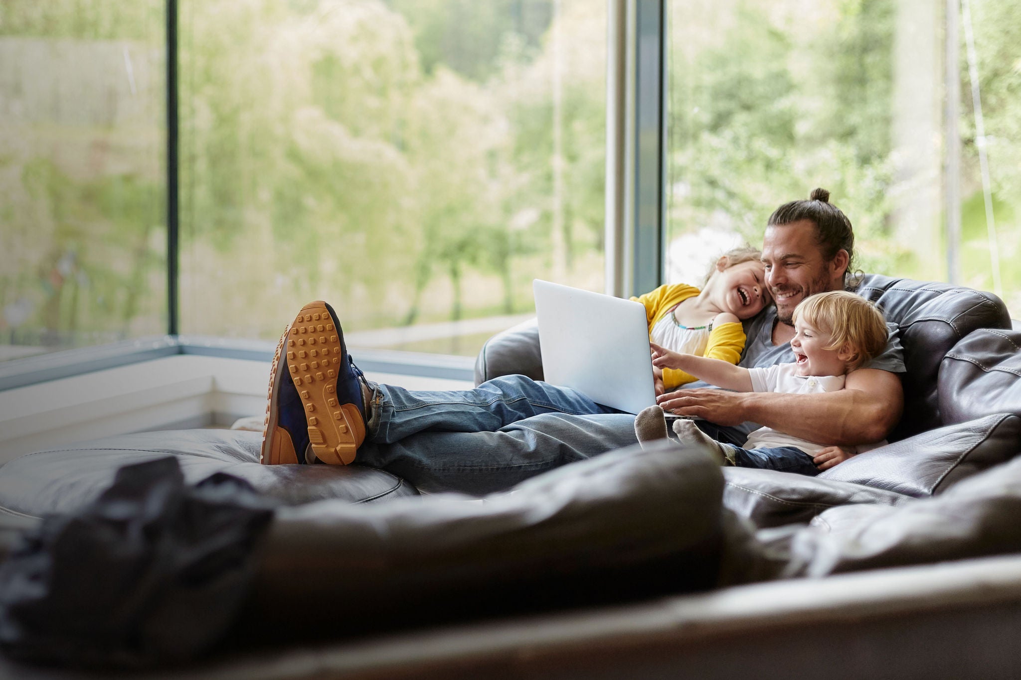 Happy father with two children looking at laptop on the couch