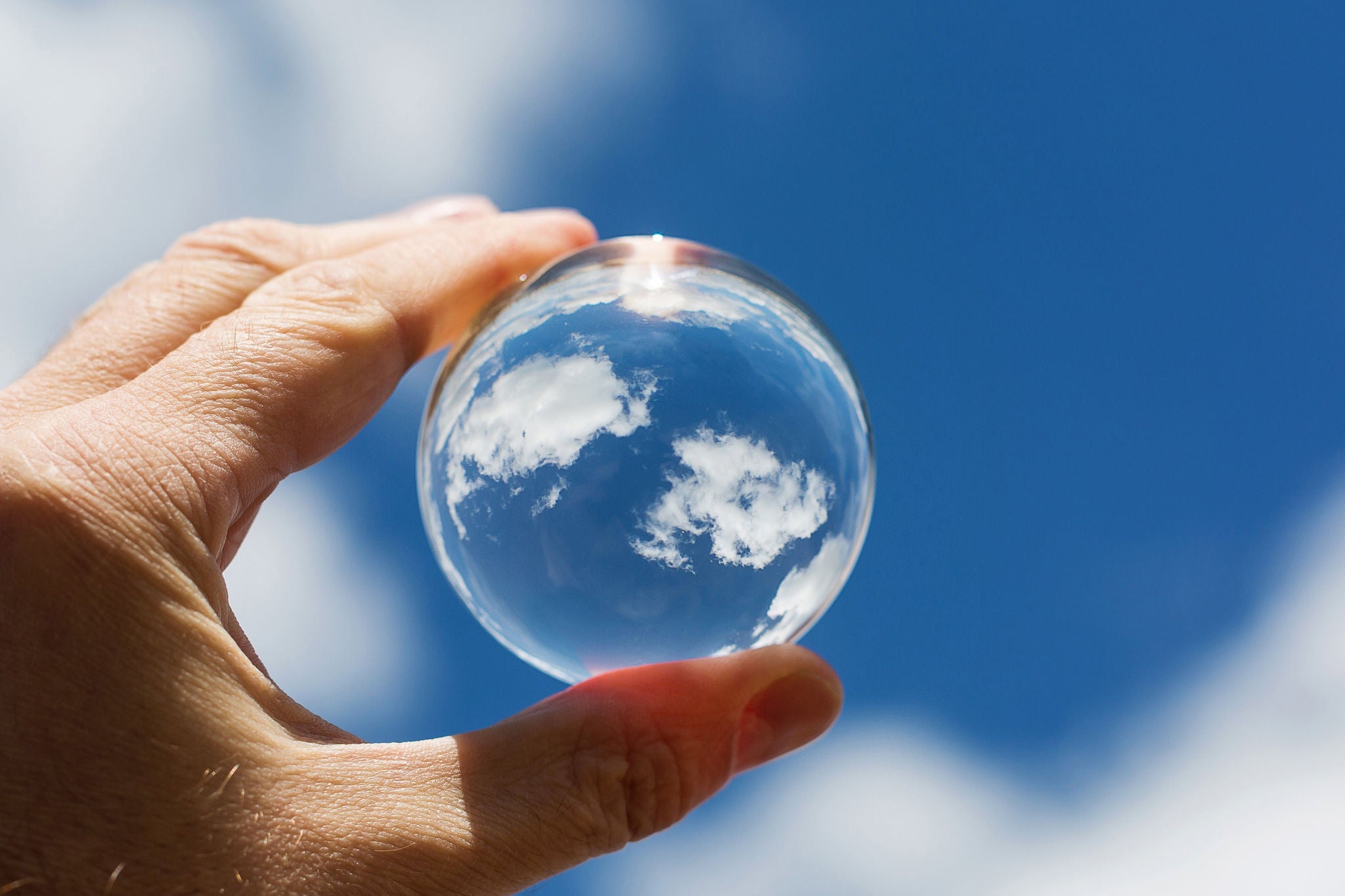 ey-main-tenant-une-sphere-de-cristal-refletant-des-nuages-dans-le-ciel-20261006