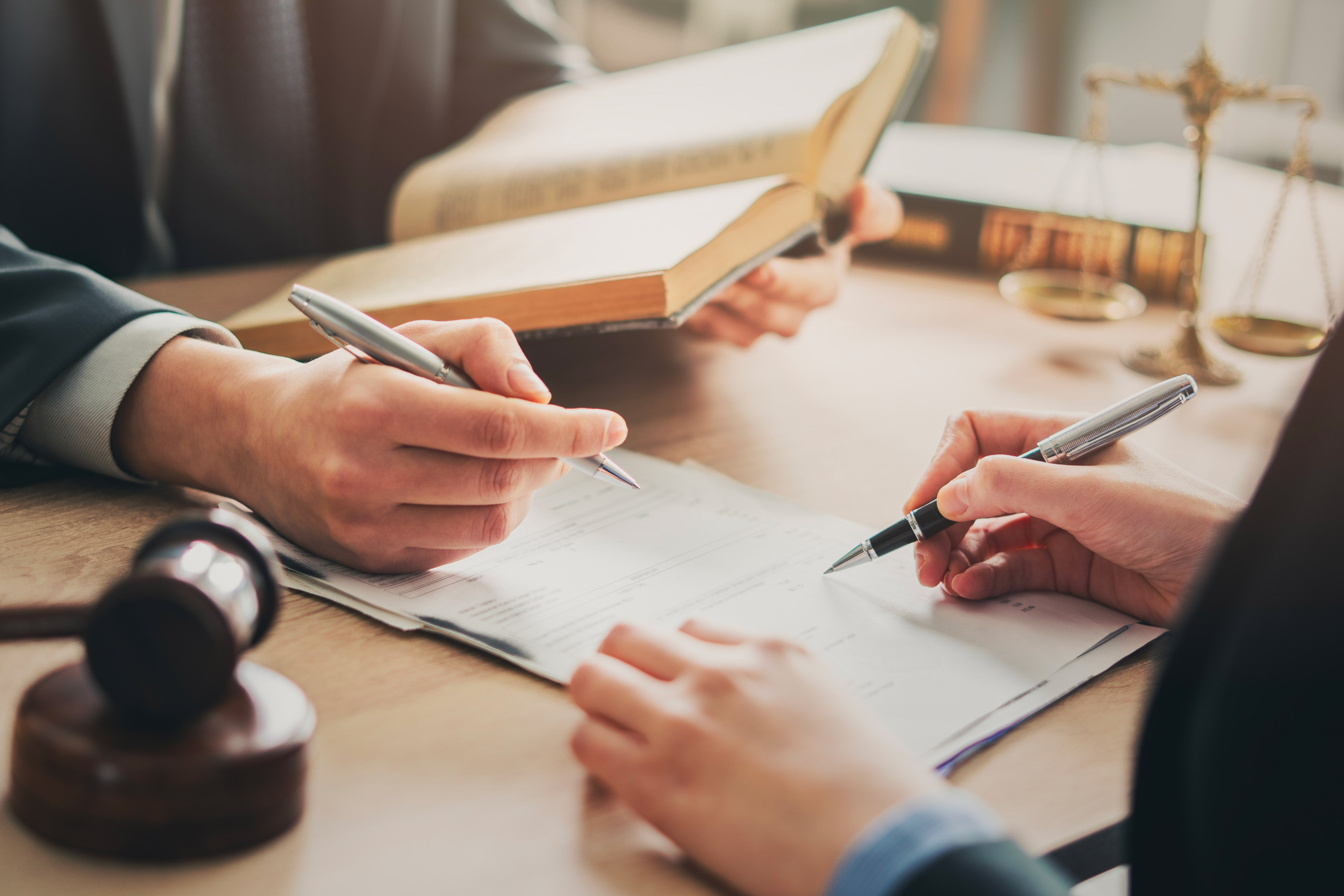 Legal professionals reviewing and signing documents at a desk.