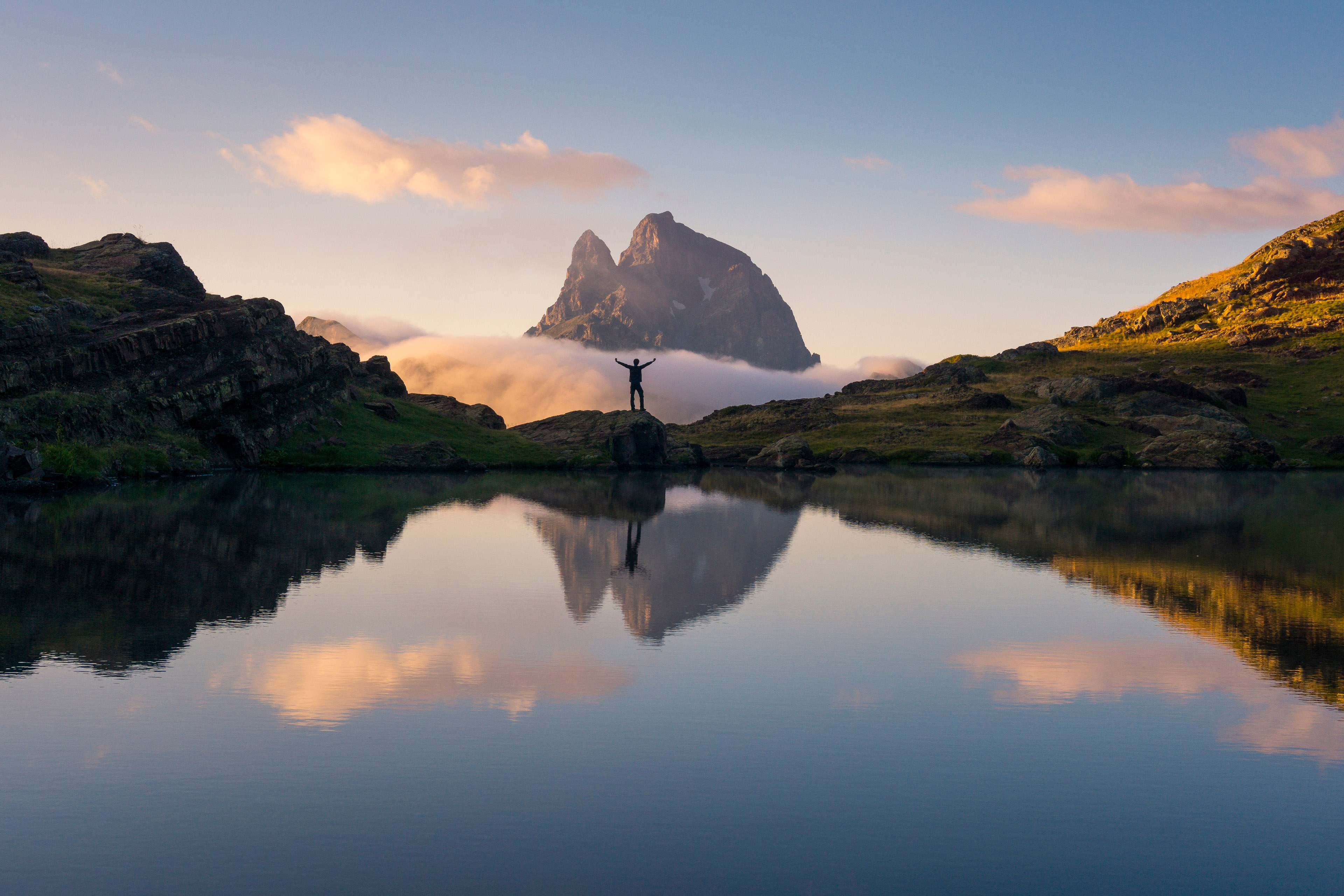 Glad turist står på en sten ved en sø