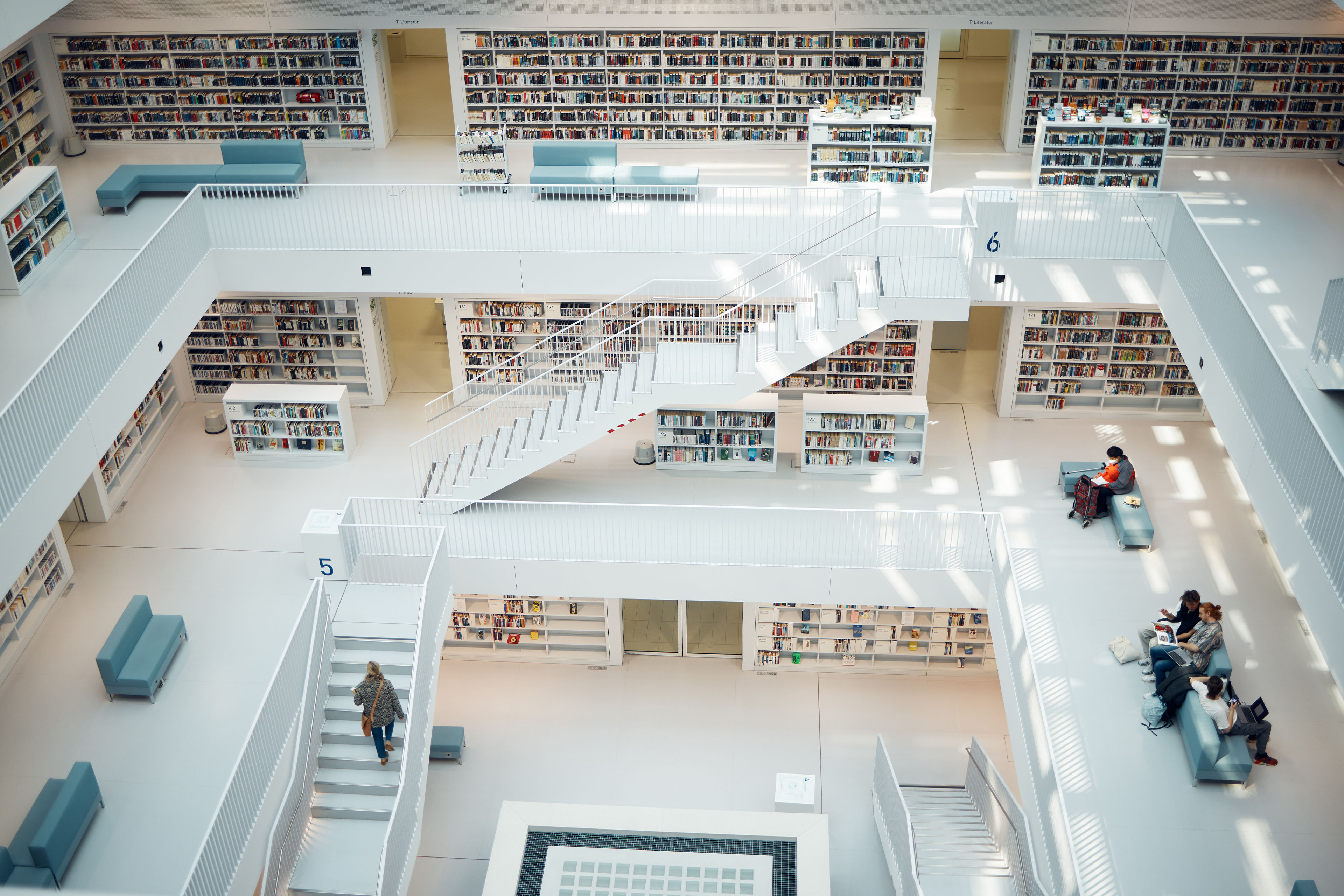Moderne Bibliothek mit offenen Ebenen, weißen Treppen und hohen Bücherregalen im Lesesaal