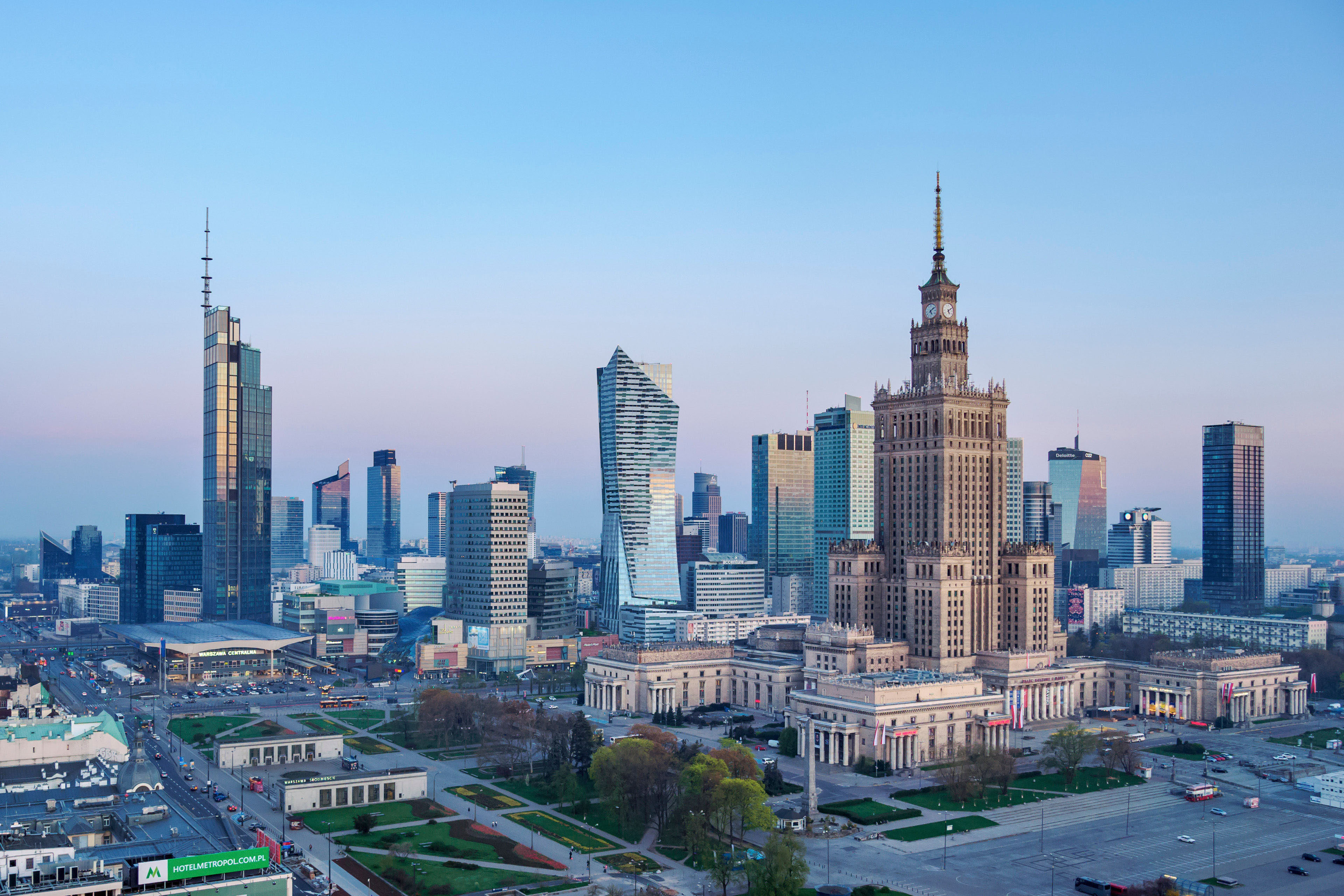 Solarzellen auf einem bluehenden Rapsfeld vor einem weissen Windpark