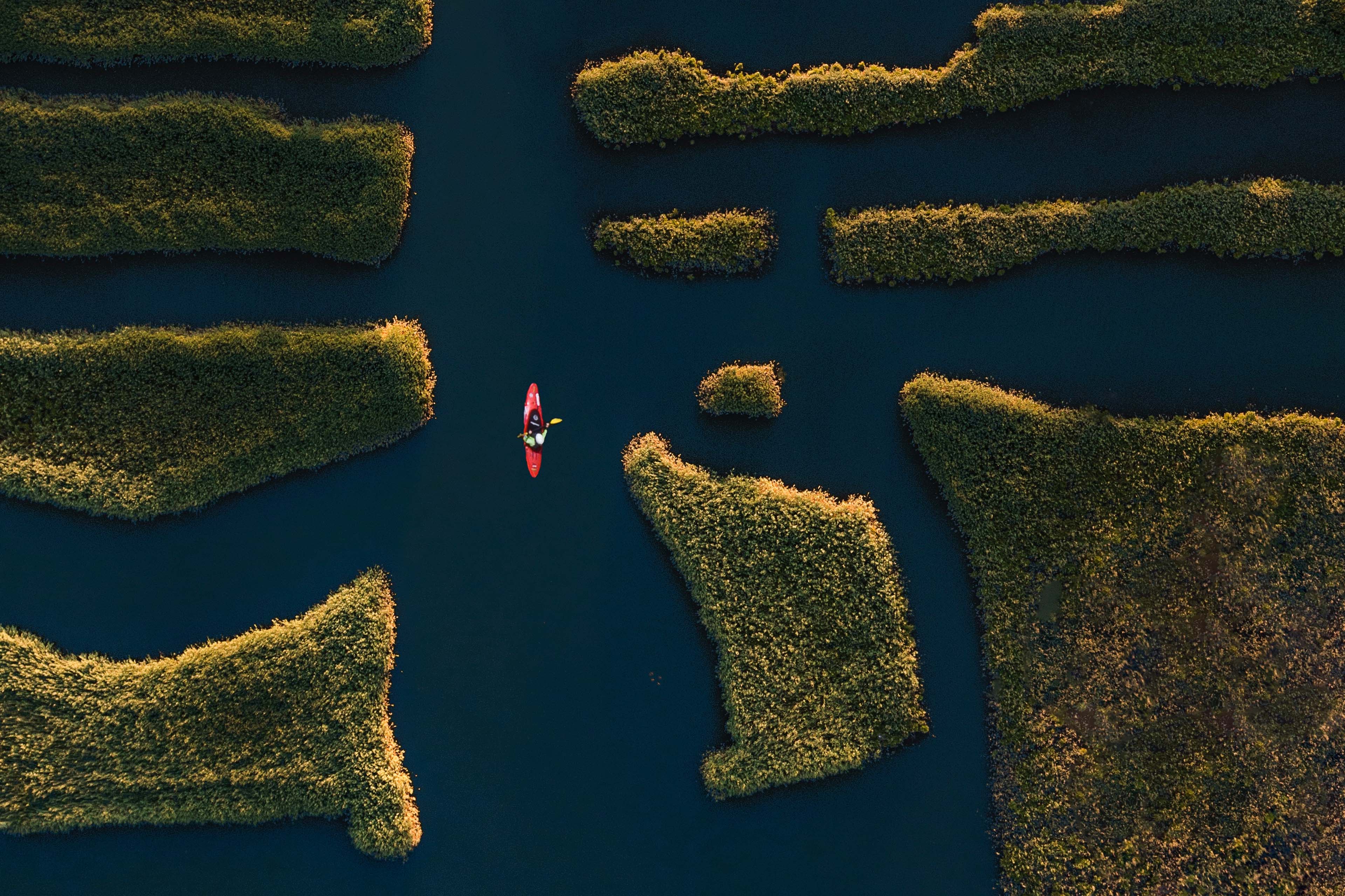 Aerial shot of kayak navigating between grassy patches of land