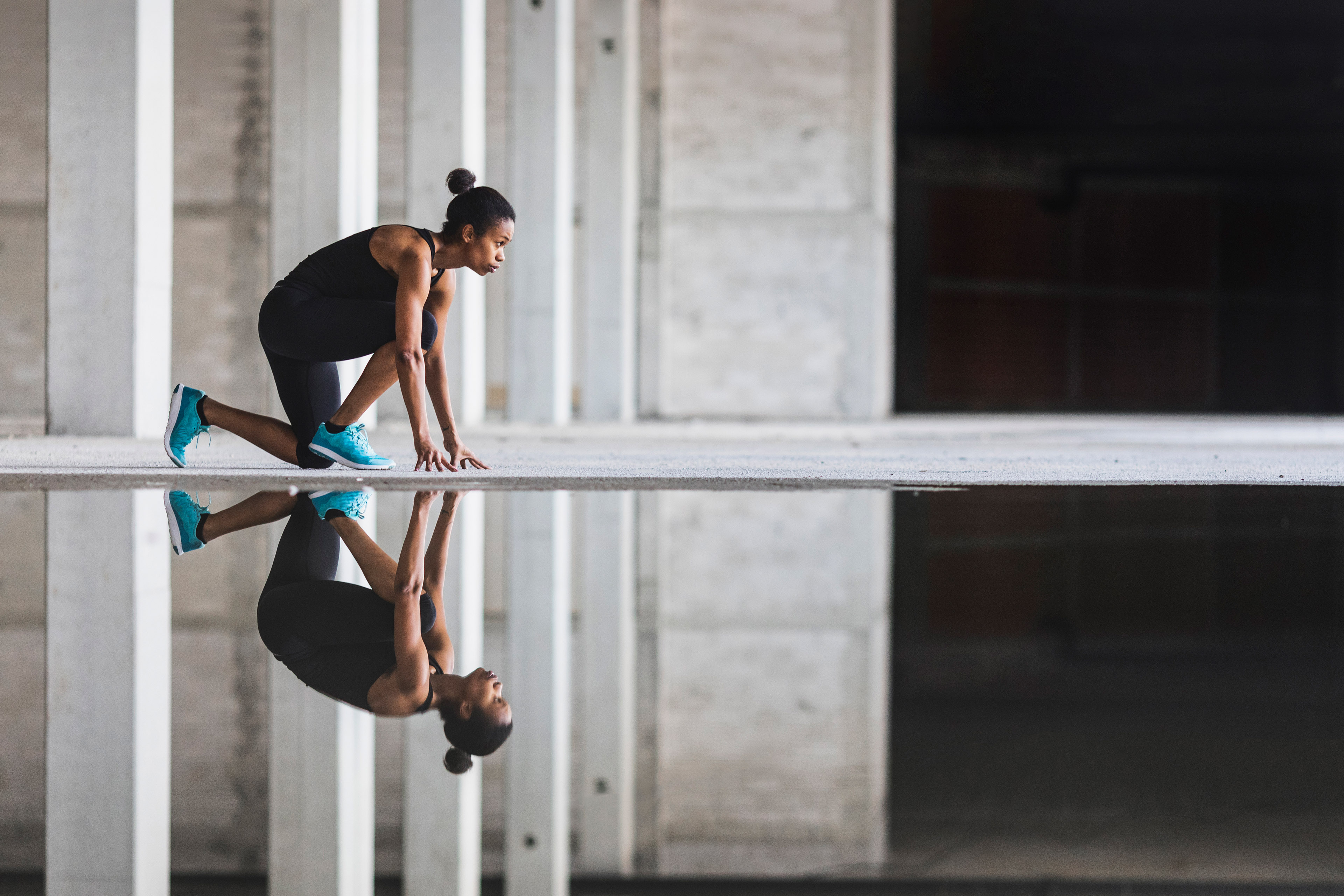 Athlete in starting position on a reflective surface in an industrial setting