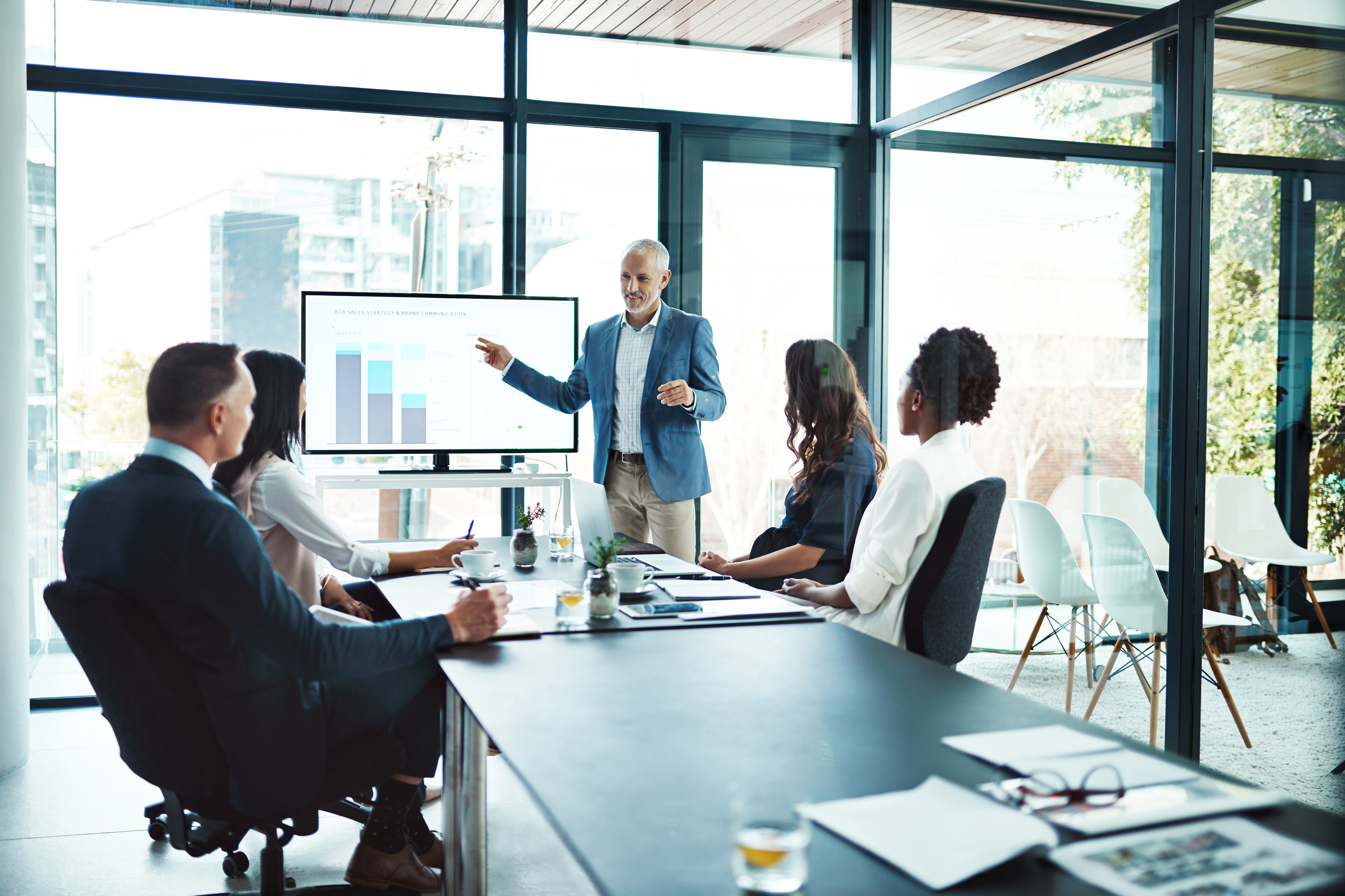 Person presents a chart on a screen during a meeting in a modern office