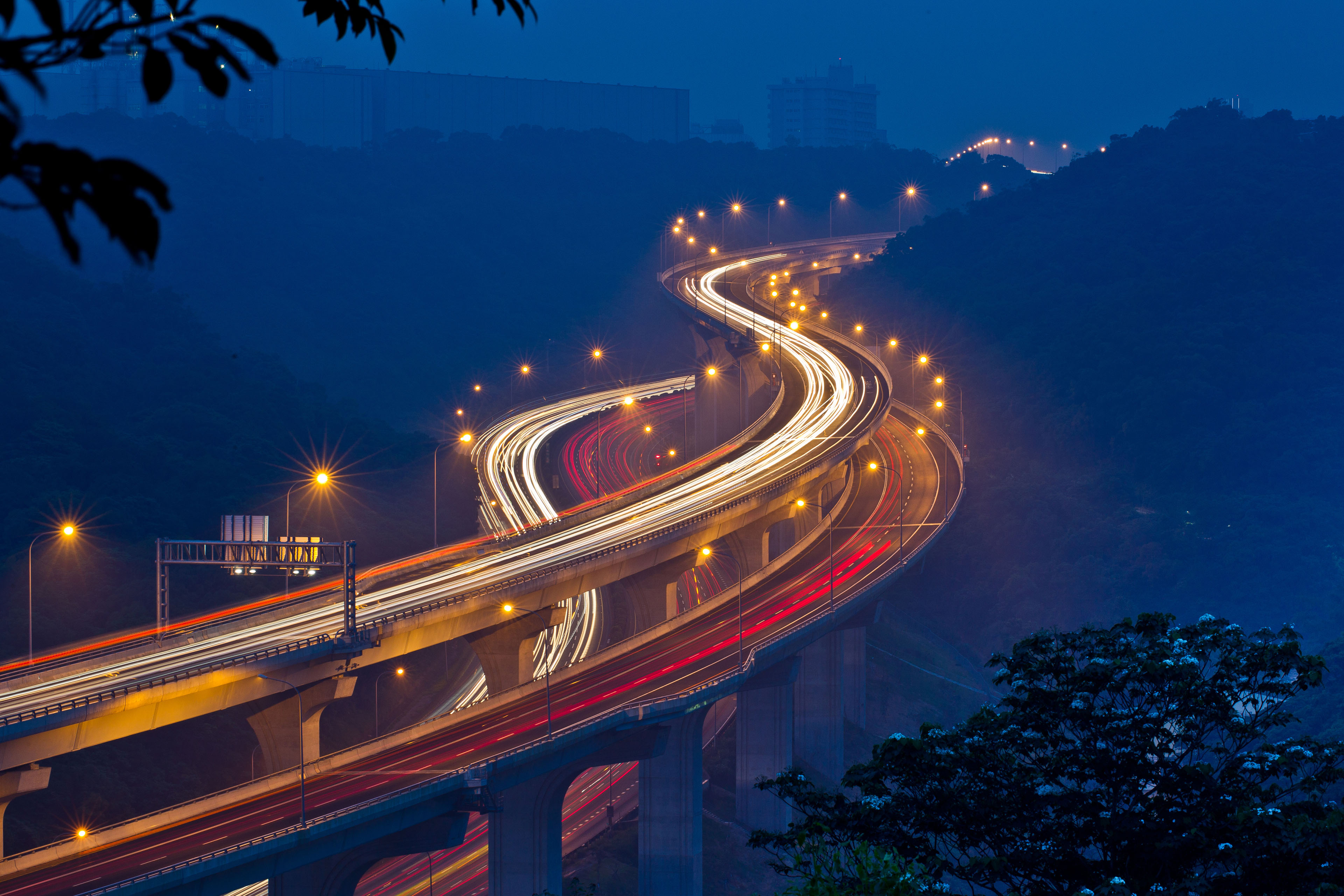 Light trails from cars on a winding highway bridge at night
