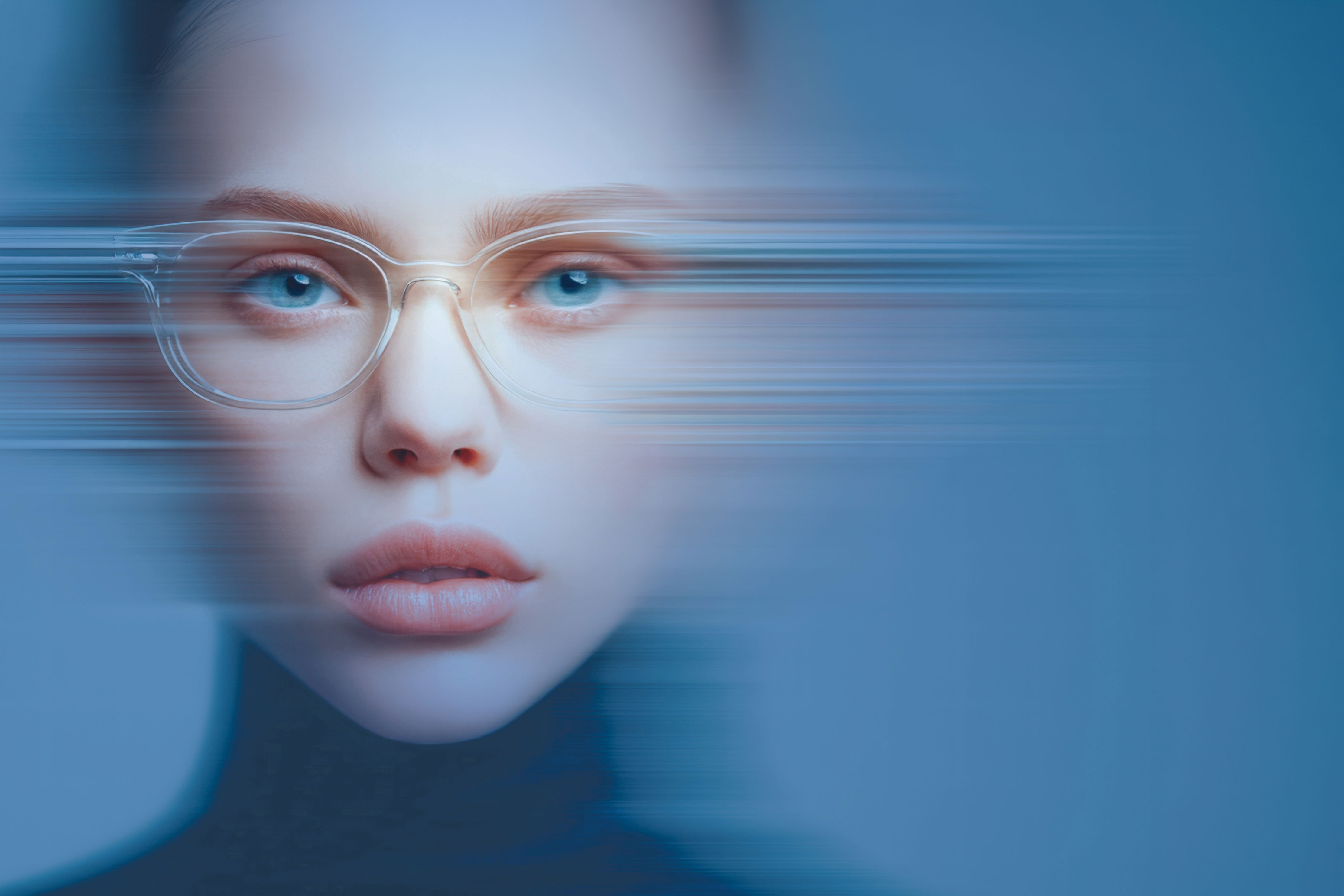 Close-up of a person with clear glasses and blue eyes, sliced by horizontal motion blur on a cool blue background.