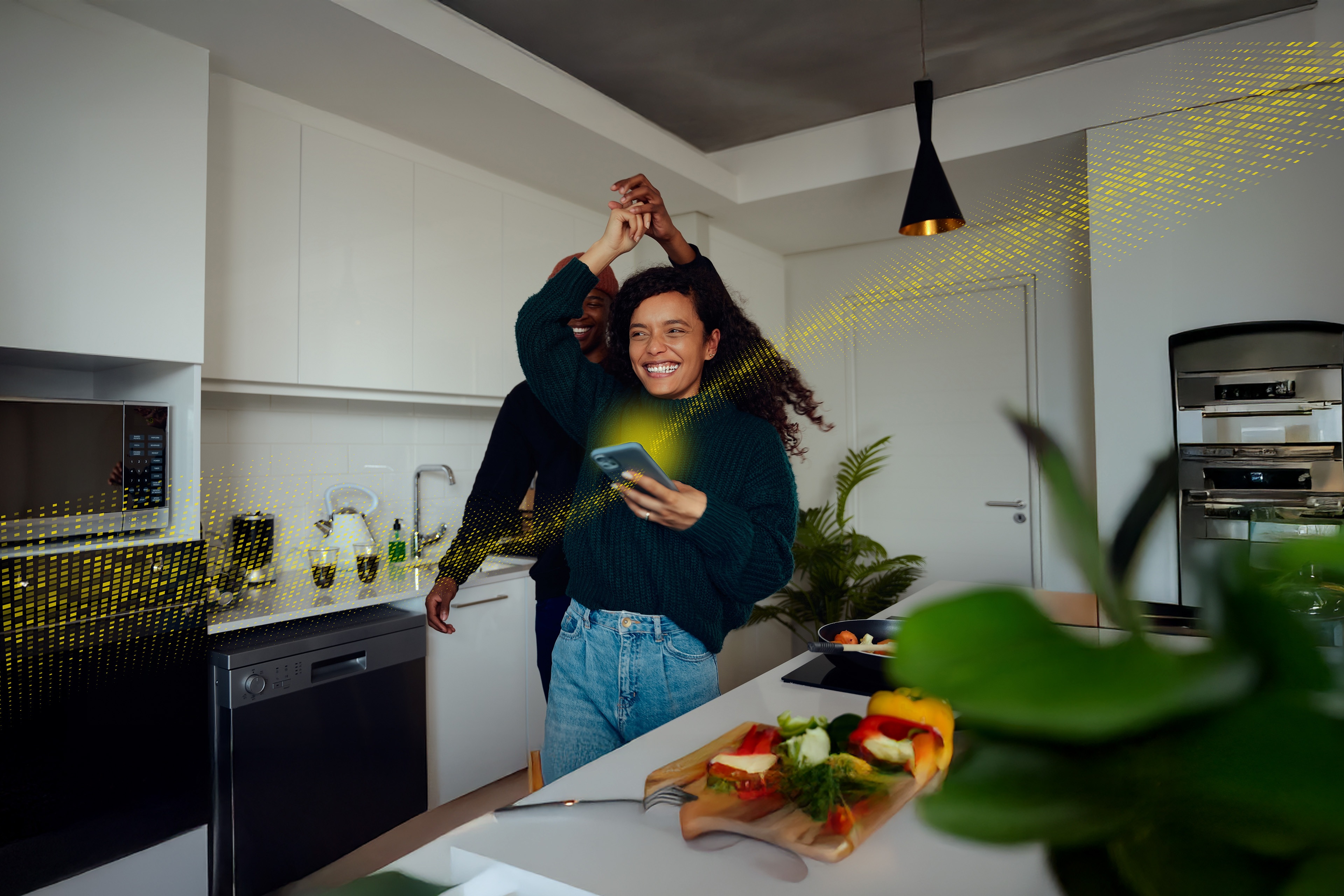 People dancing in a modern kitchen while using a smartphone