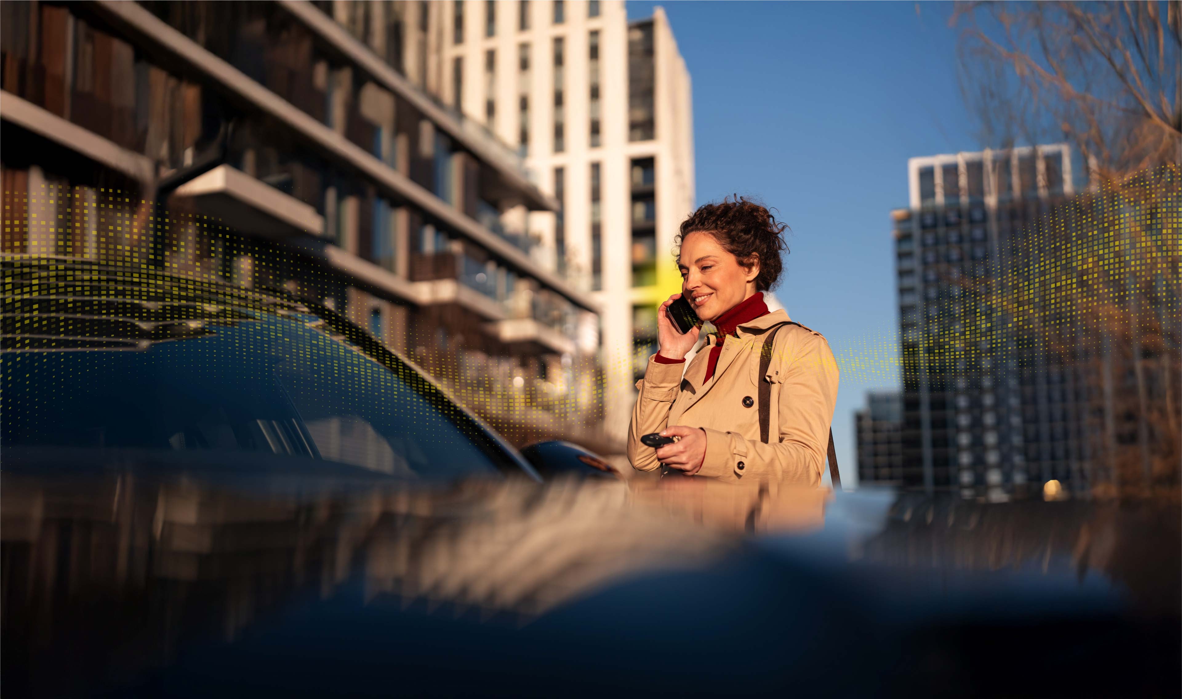 Person using a mobile phone while standing on a city street surrounded by modern buildings