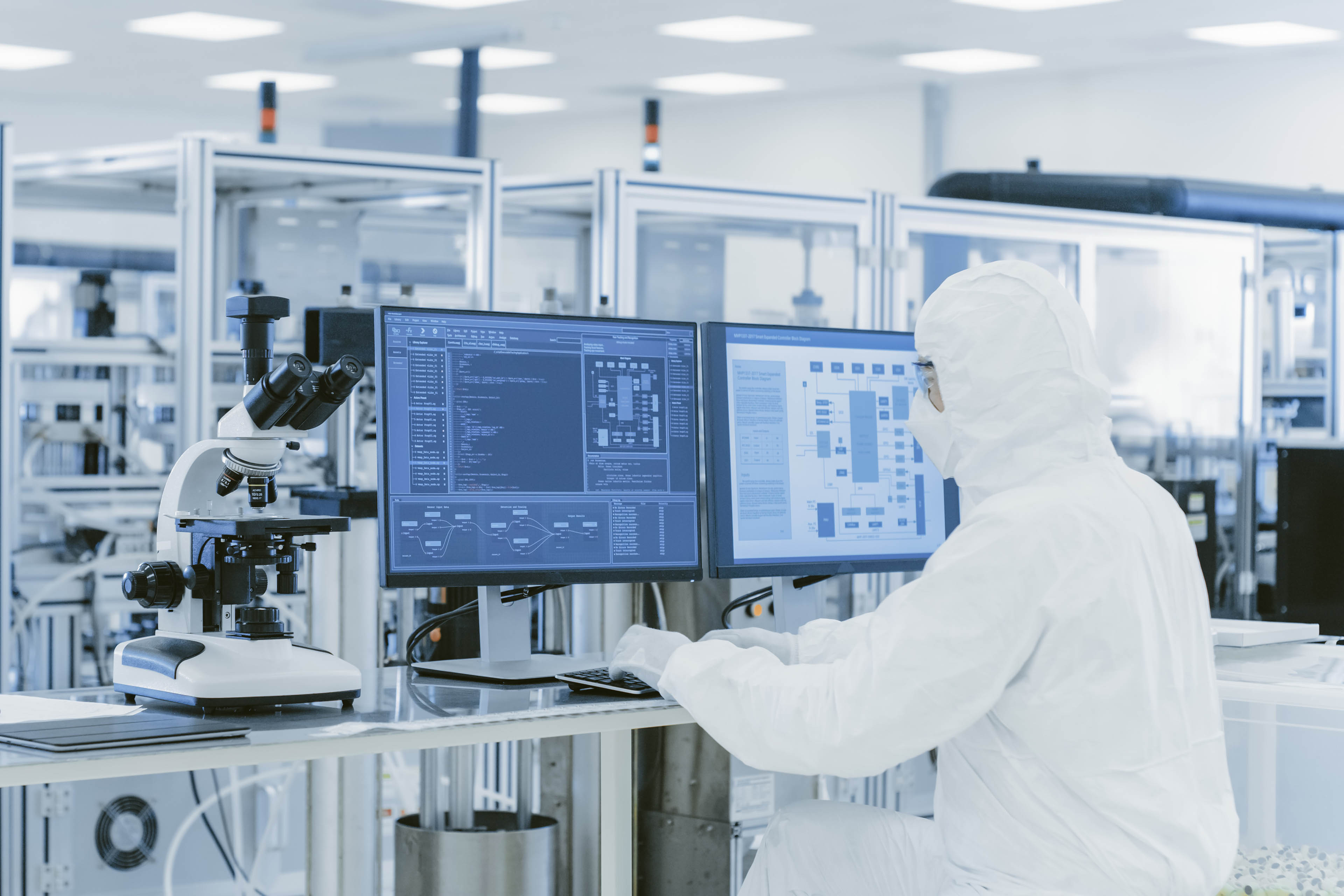 In Laboratory Over the Shoulder View of Scientist in Protective Clothes Doing Research on a Personal Computer.