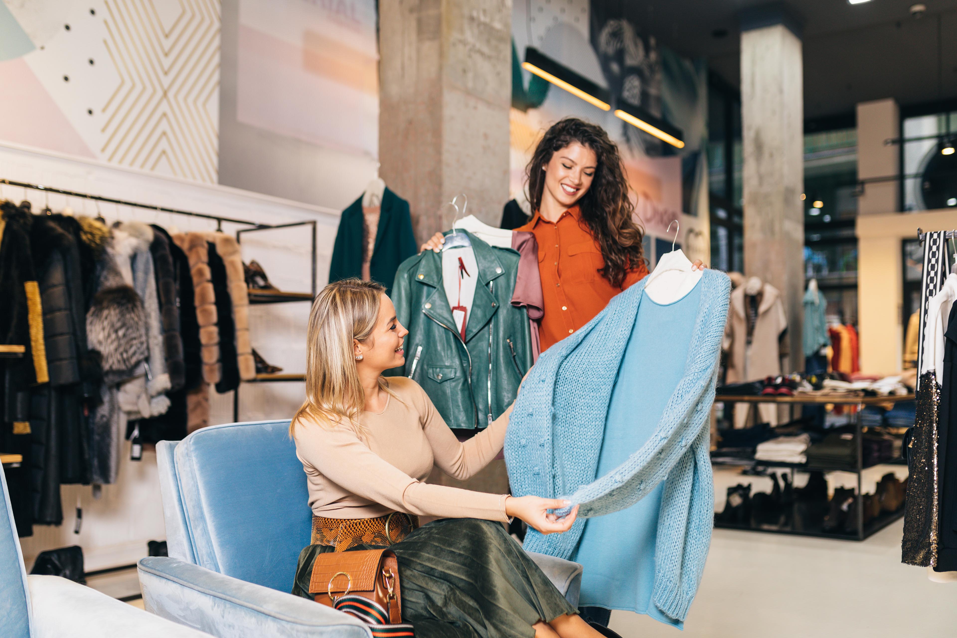 Female seller helps buyer to choose between diferent clothes.