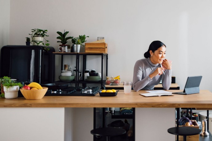 Asian businesswoman using digital tablet at kitchen desk