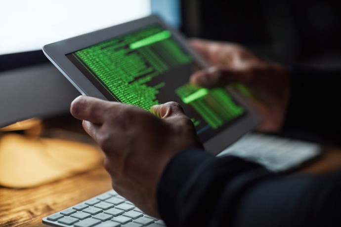 Unidentifiable hacker cracking computer code in dark