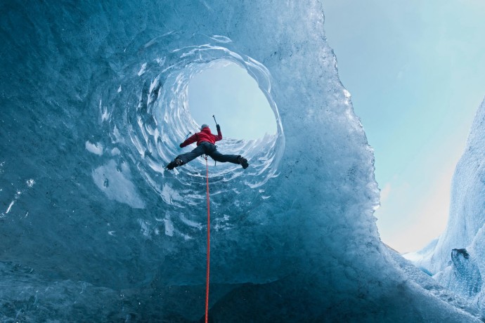 Woman climbing out of glacial cave