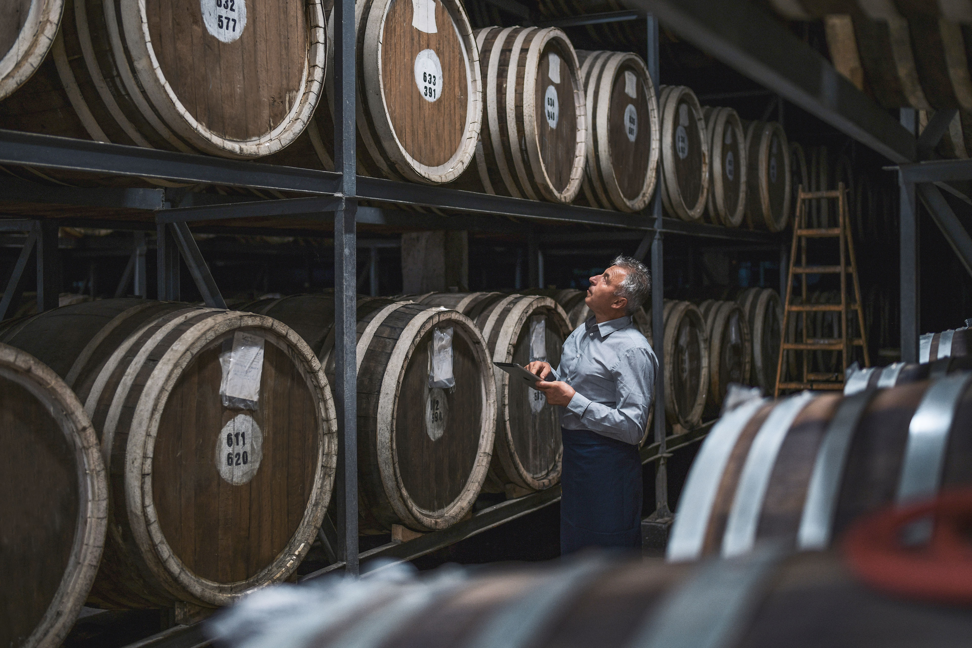 Worker examining barrels in warehouse
