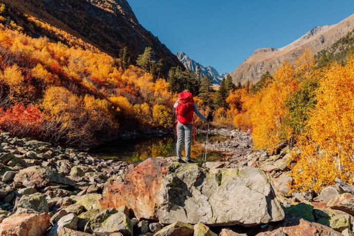 Female hiker with backpack enjoying view in the autumnal mountains
