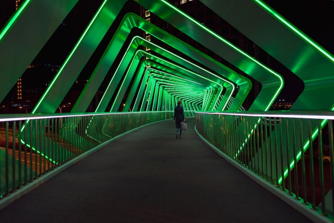 ey women crossing a pedestrian bridge with light effects