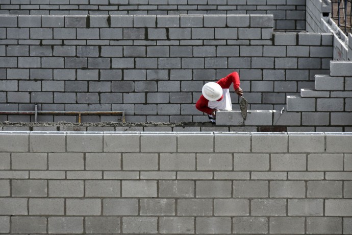 A man constructs the brick wall with bricklayers.