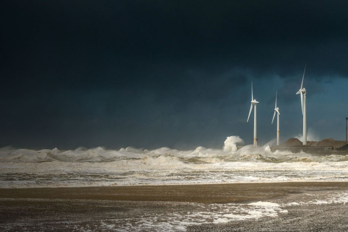 Four wind turbines amidst fierce storm waves and clouds