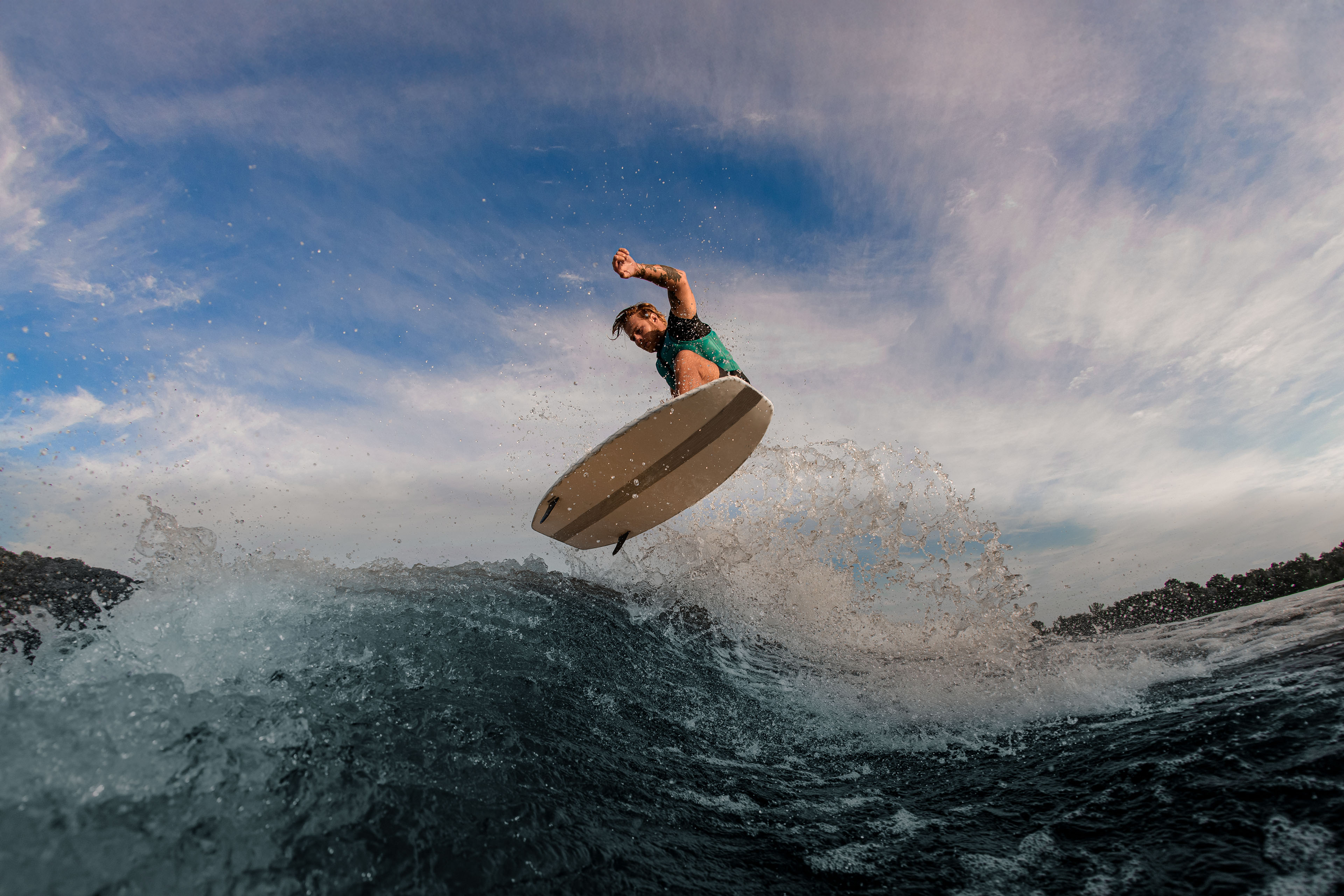 Beautiful view of active male athlete flying in the air on wakesurf over splashing wave