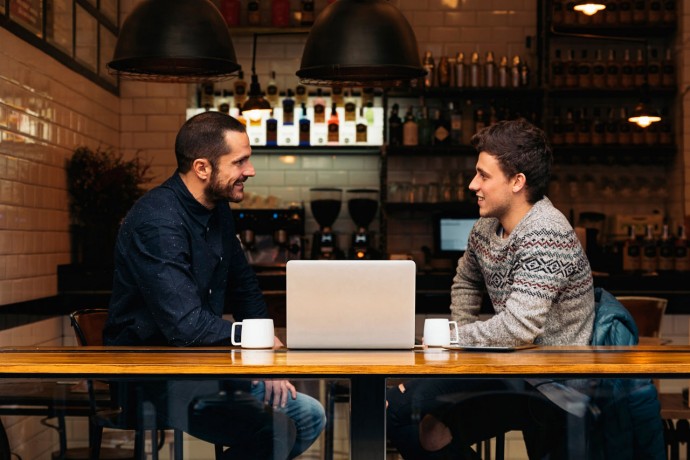 Friends talking over laptop in a coffee shop