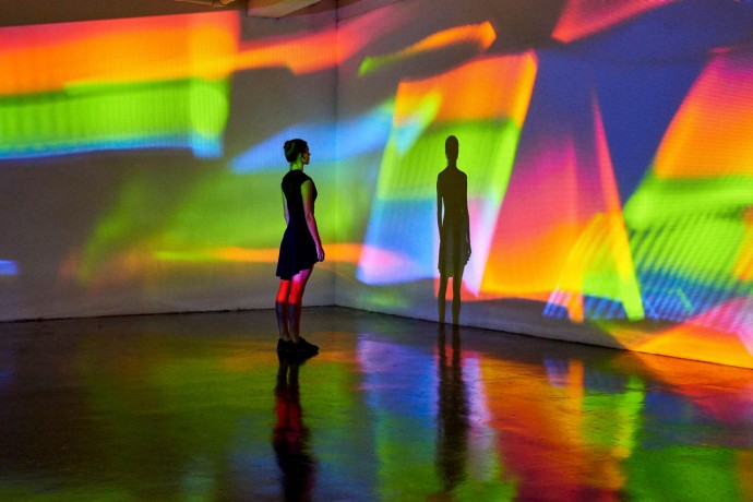 Girl looking at a large scale image of projected patterns in a gallery space