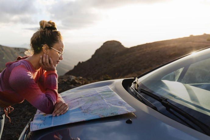Side view of women looking at the map on her car