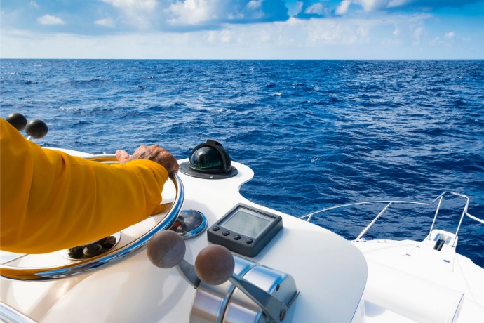 Captain in yellow jacket steering a yatch