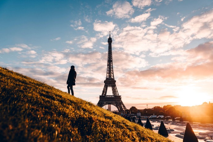 Woman on a grassy hill looking at the Eiffel Tower