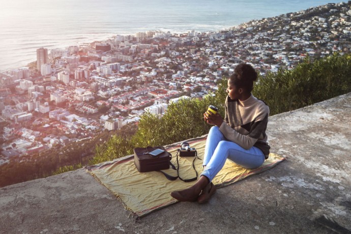 A solo female traveller looks down over cape town background