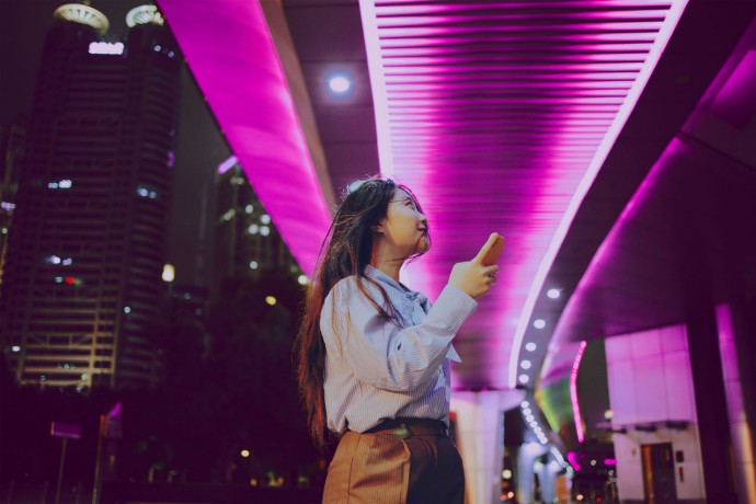 Asian woman standing under a brightly lit pedestrian bridge