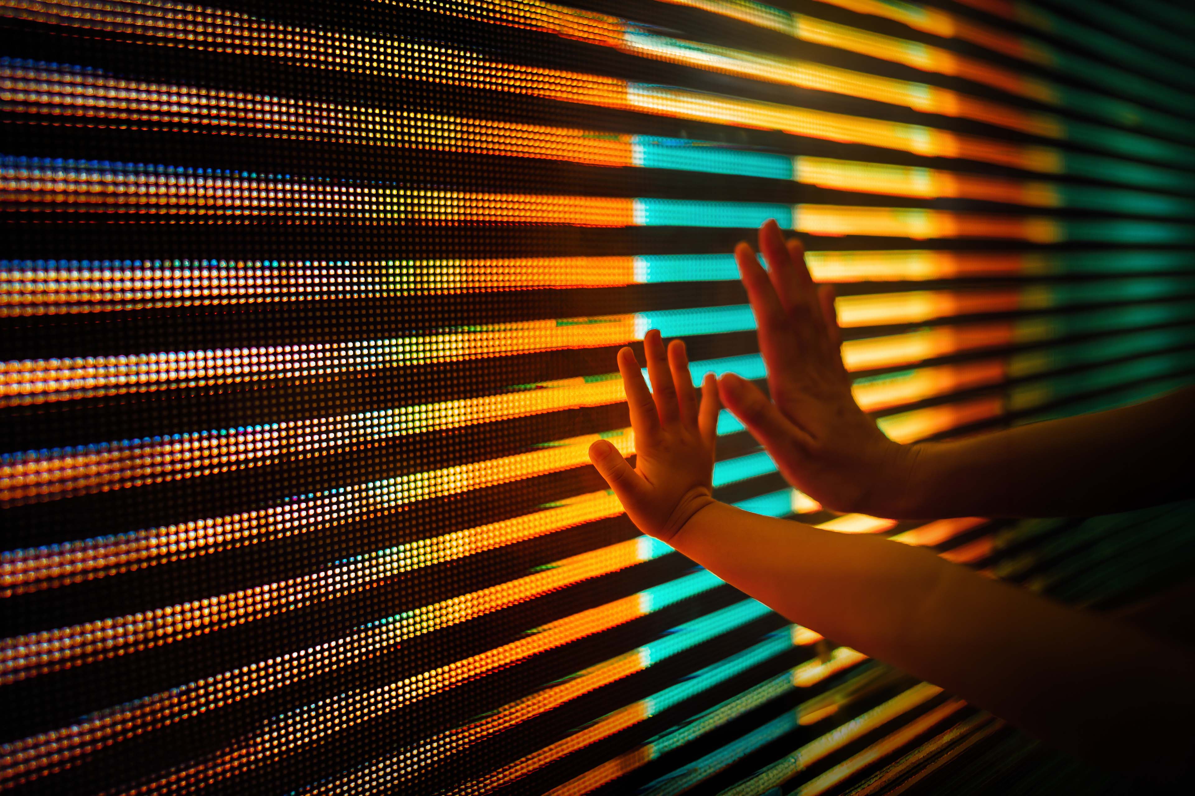 Close-up of mother and child's hand touching illuminated led display