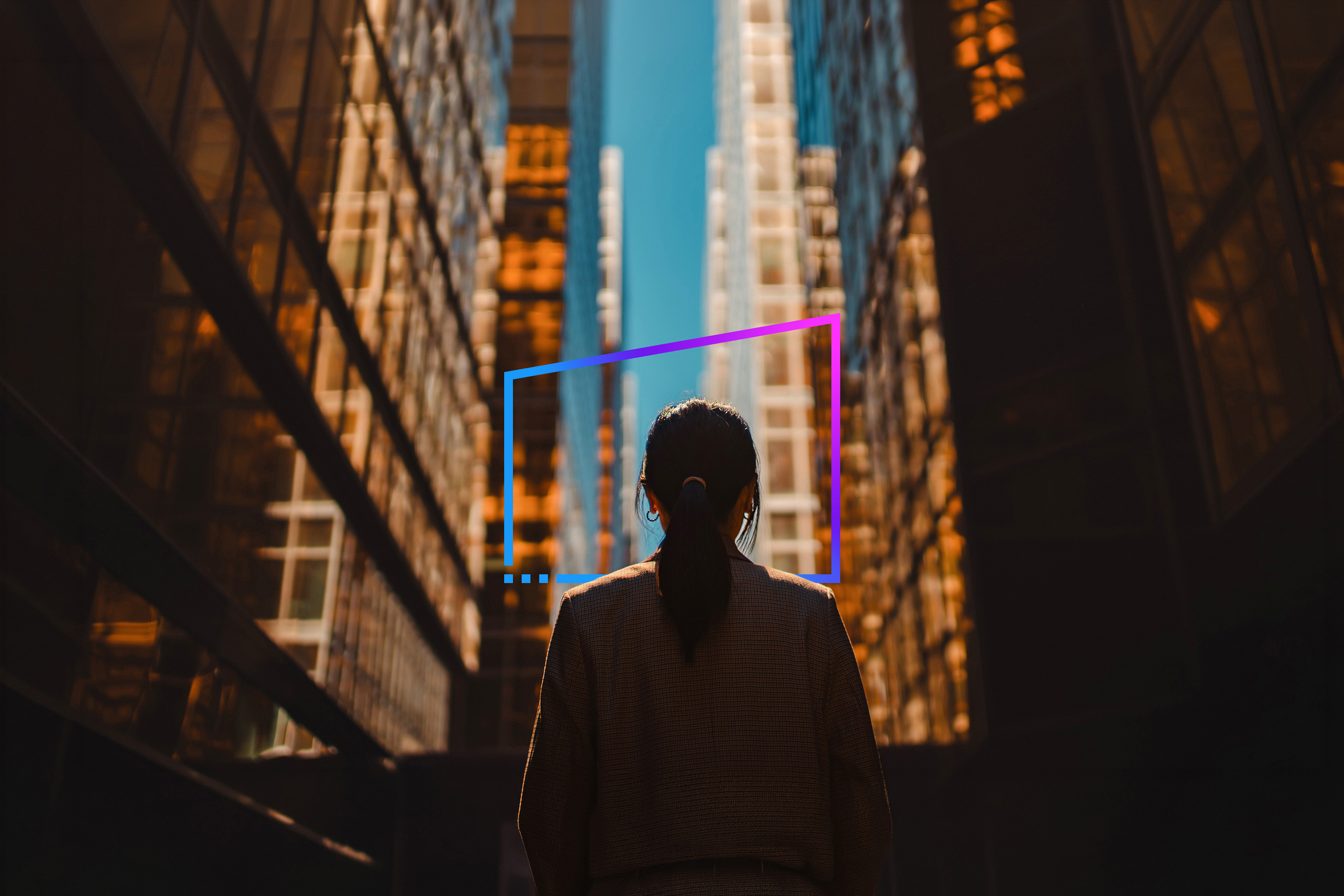 Rear view of businesswoman standing against facade of skyscrapers