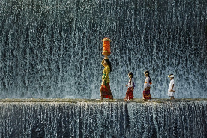 balinese woman and children wearing traditional dress on waterfall