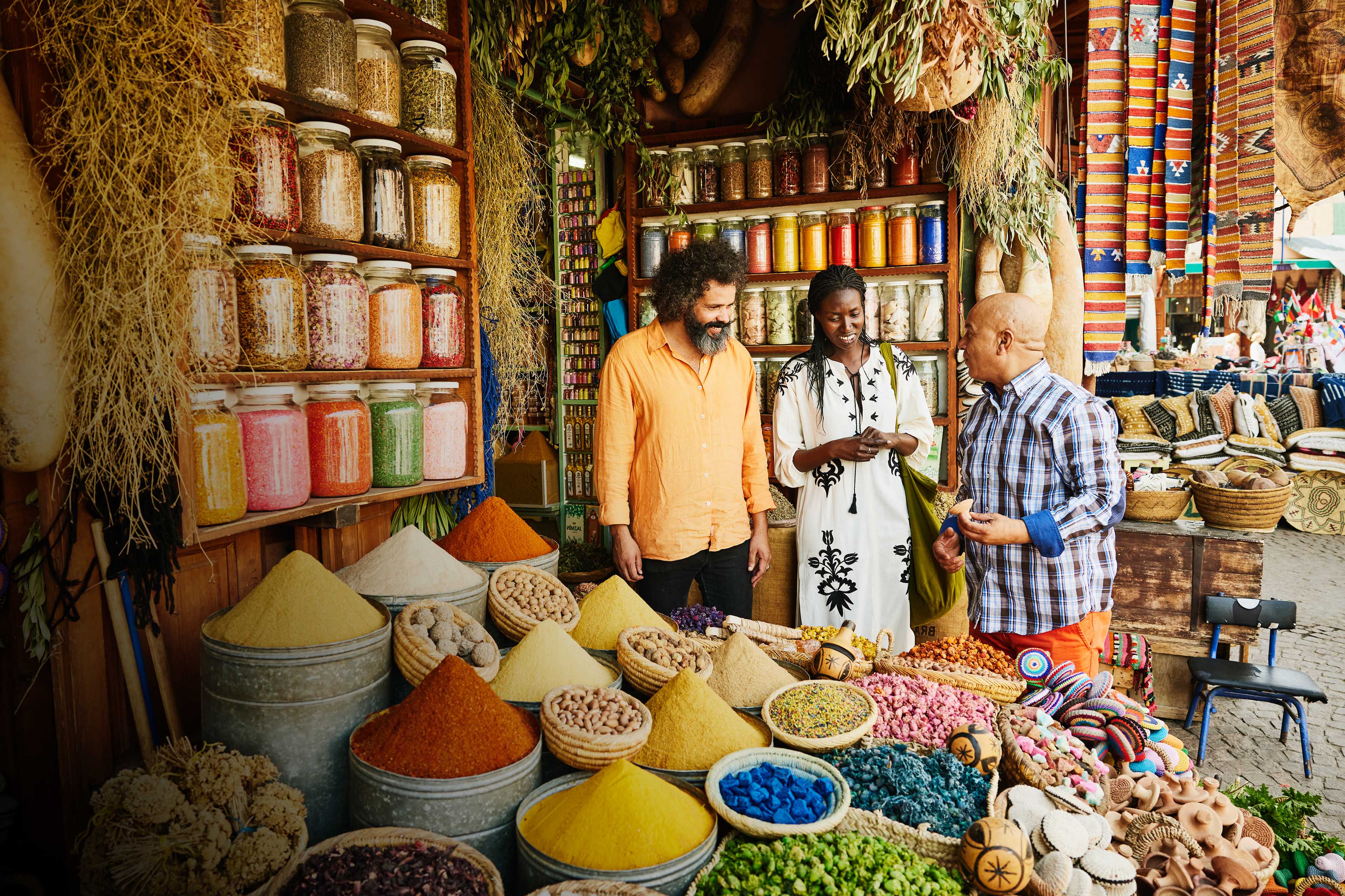 Couple talking to shop owner while shopping in spice shop in the souks of Marrakech during vacation