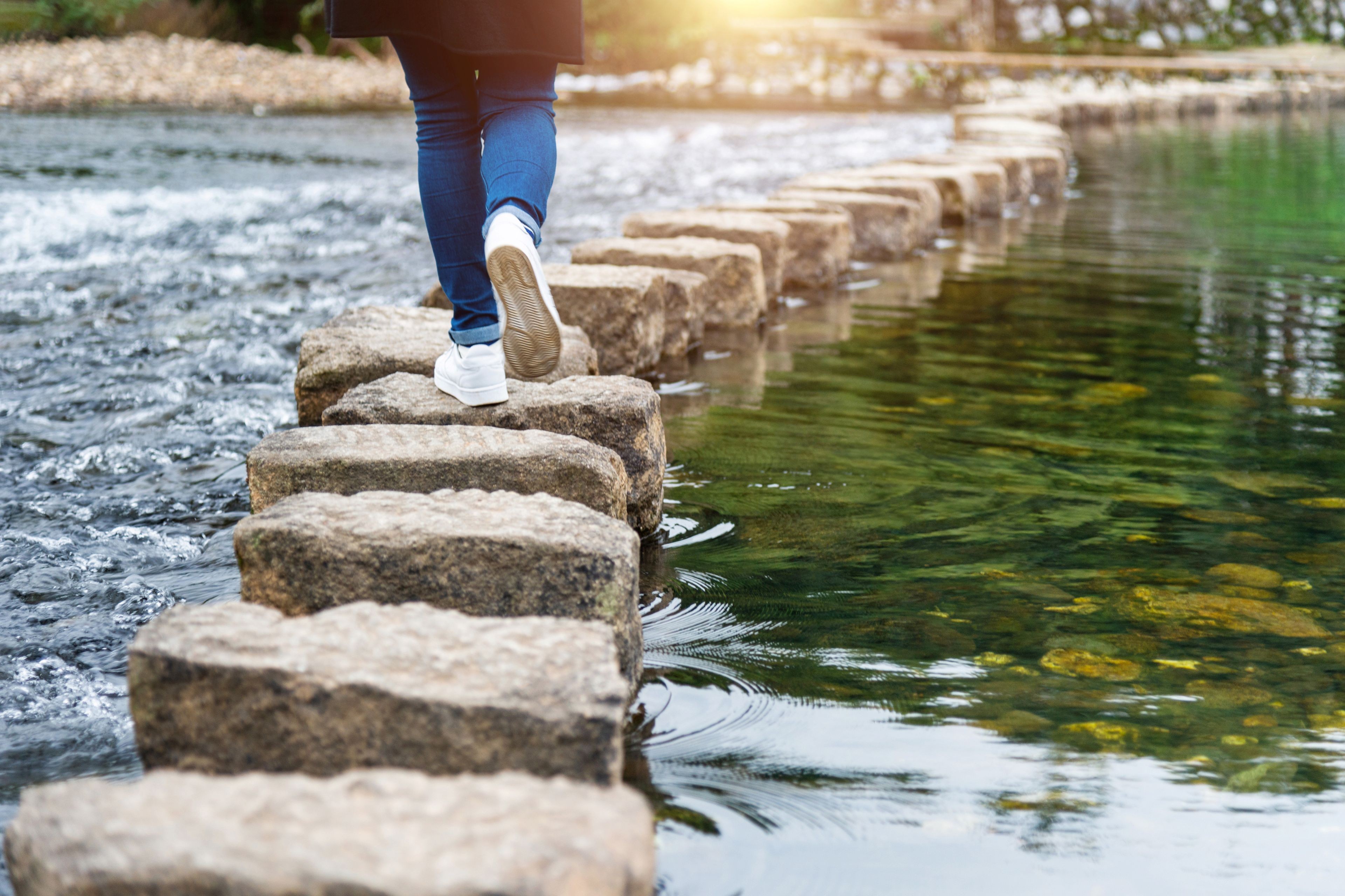 Woman crossing a river on stepping stones