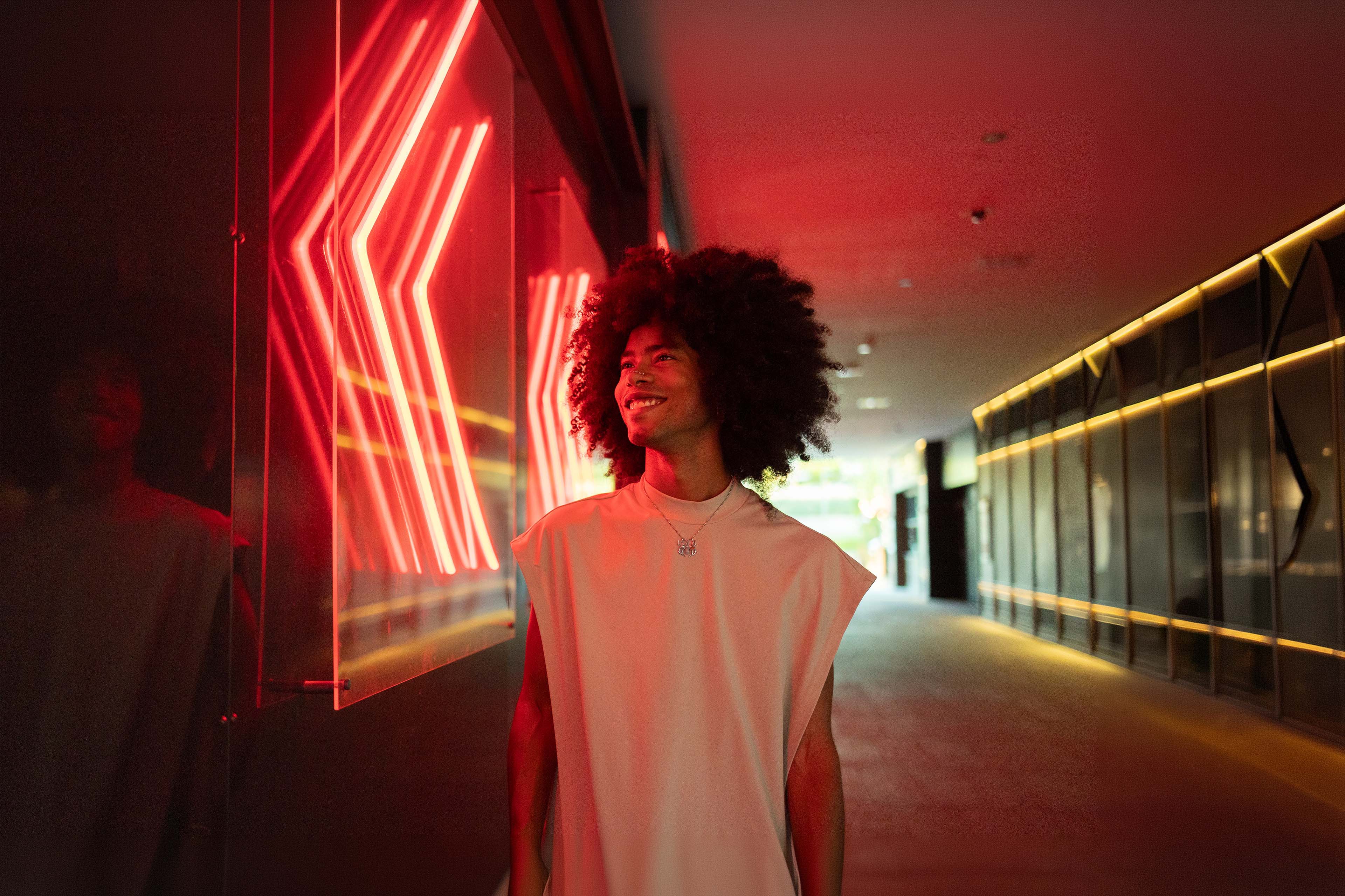 Smiling young man standing near illuminated wall